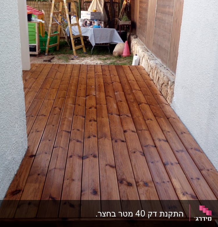 דק עץ חום בין קירות לבנים בגינה